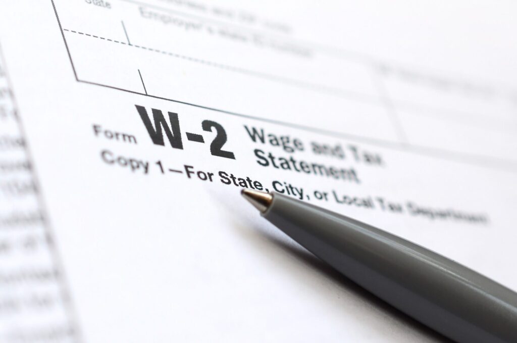 The pen lies on the tax form W-2 Wage and Tax Statement. The time to pay taxes