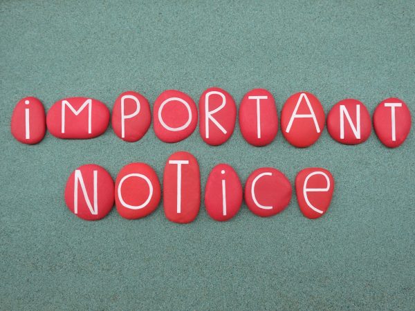 Important notice text composed with red colored stone letters over green sand